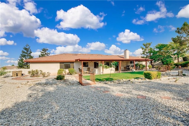 single story home featuring a patio area, a chimney, a front lawn, and stucco siding