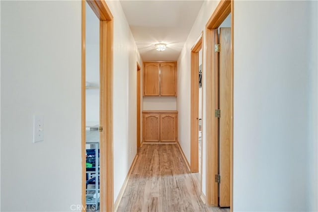 hallway with light wood-style flooring and baseboards