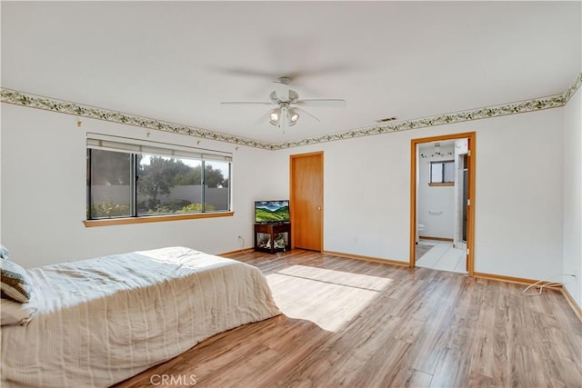 bedroom with ensuite bath, light wood-style flooring, visible vents, and baseboards