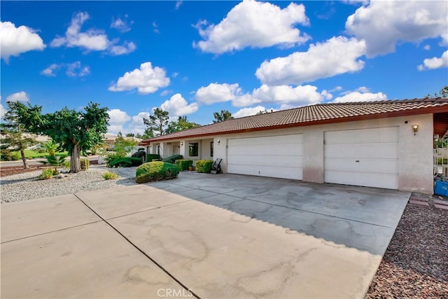 ranch-style house with a garage, a tiled roof, concrete driveway, and stucco siding