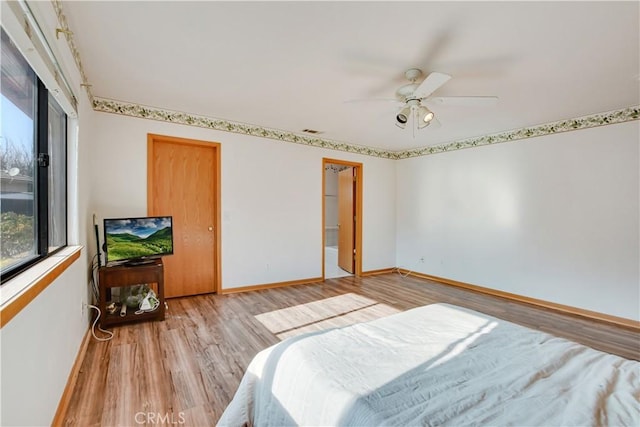 bedroom featuring light wood finished floors, visible vents, baseboards, and a ceiling fan