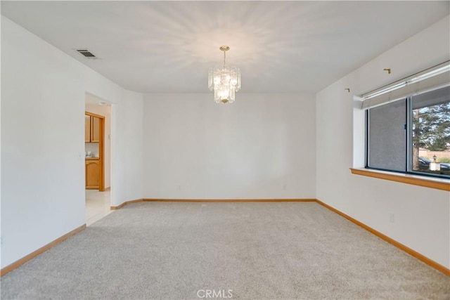 carpeted empty room featuring a chandelier, visible vents, and baseboards