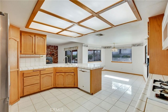 kitchen featuring visible vents, light tile patterned flooring, white dishwasher, a sink, and a peninsula