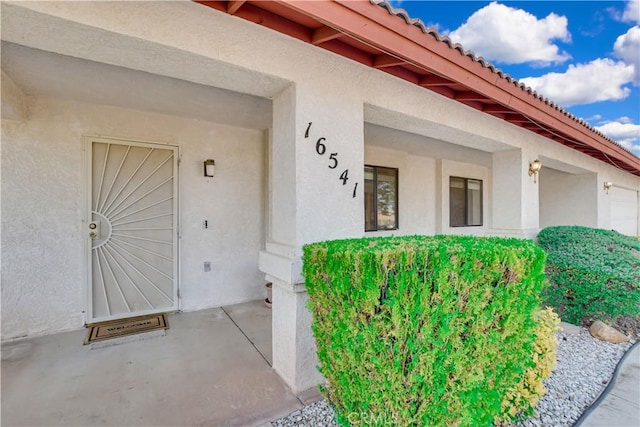 doorway to property featuring a tile roof and stucco siding