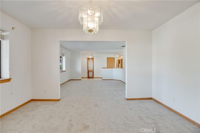 unfurnished room featuring carpet floors, baseboards, and a notable chandelier