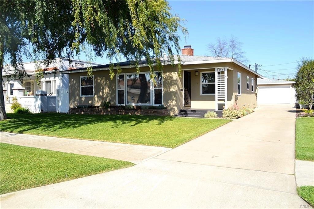 view of front facade featuring a garage, an outdoor structure, and a front yard