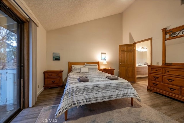 bedroom featuring lofted ceiling, hardwood / wood-style flooring, access to exterior, connected bathroom, and a textured ceiling