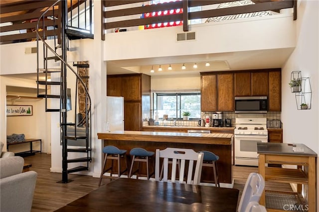 kitchen featuring hardwood / wood-style flooring, appliances with stainless steel finishes, kitchen peninsula, and decorative backsplash