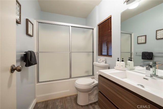 full bathroom with vanity, combined bath / shower with glass door, hardwood / wood-style floors, and toilet