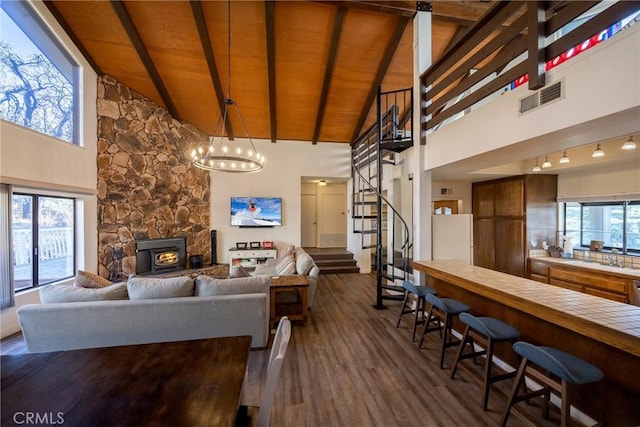 living room featuring dark wood-type flooring, high vaulted ceiling, beamed ceiling, wooden ceiling, and a chandelier