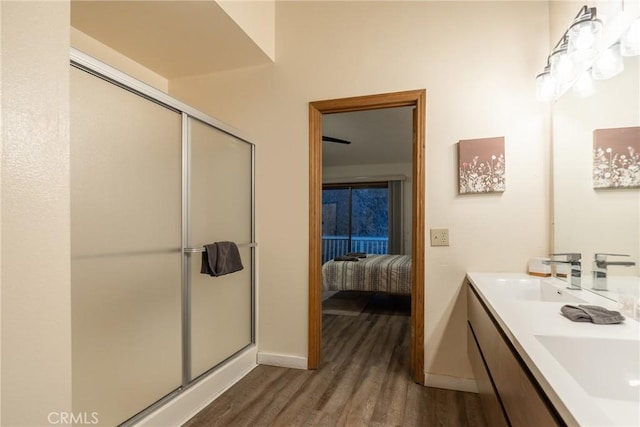 bathroom with wood-type flooring, a shower with shower door, and vanity