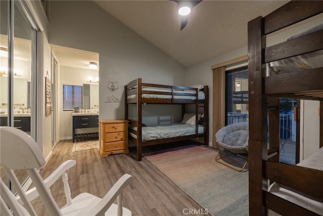 bedroom with connected bathroom, lofted ceiling, sink, ceiling fan, and light wood-type flooring