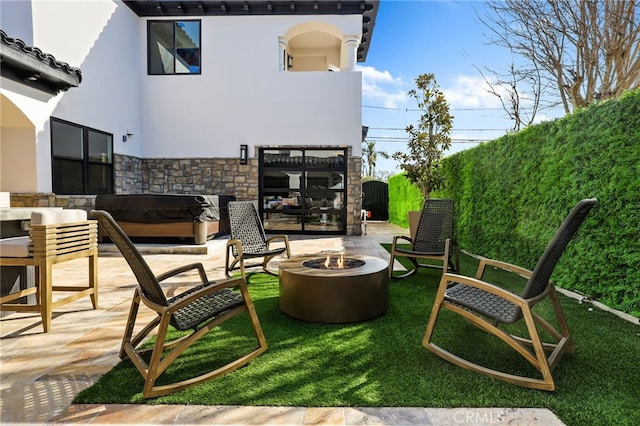 view of patio with a hot tub and a fire pit