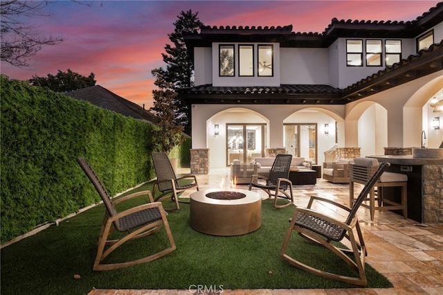 back house at dusk with a patio and an outdoor living space with a fire pit