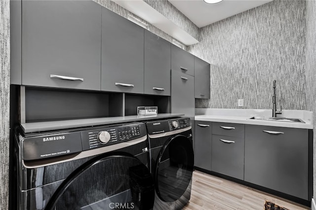 washroom with cabinets, sink, washing machine and clothes dryer, and light hardwood / wood-style flooring