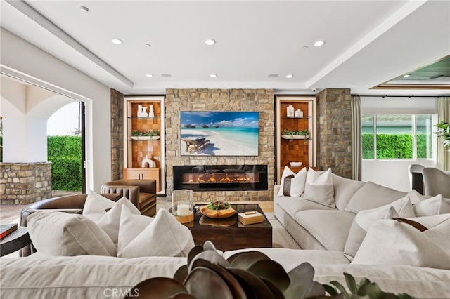 living room with built in shelves and a raised ceiling