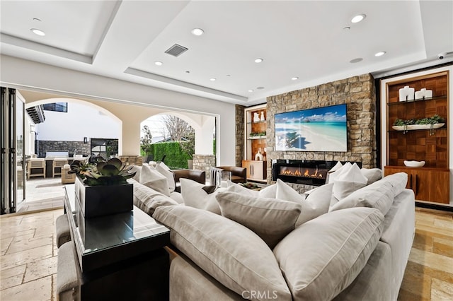 home theater with built in shelves, a fireplace, and a raised ceiling