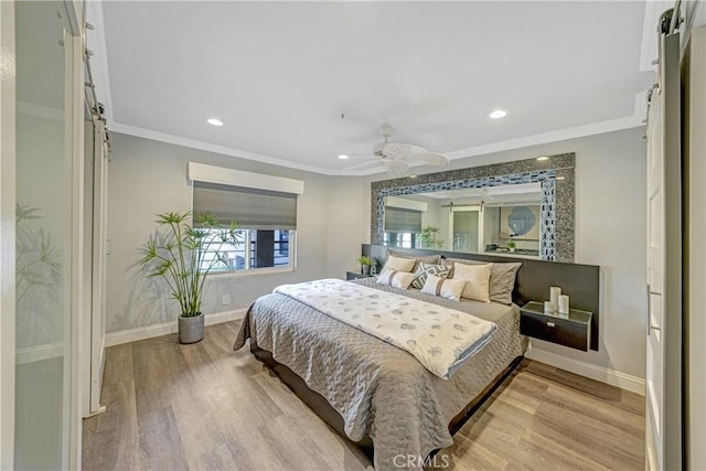 bedroom featuring ornamental molding, light hardwood / wood-style floors, and a barn door