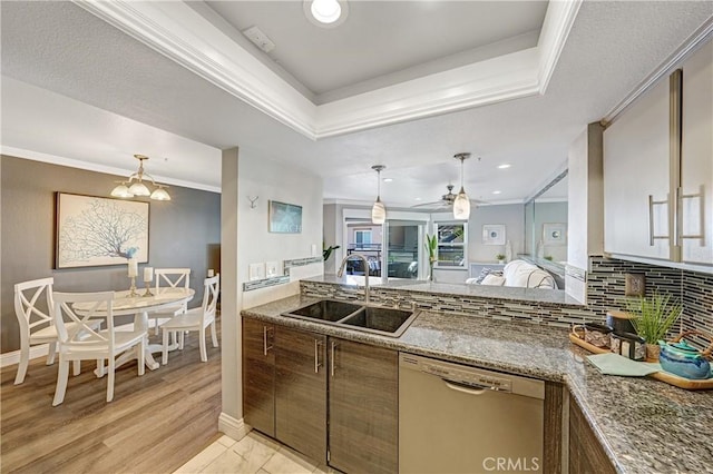 kitchen with a raised ceiling, dishwasher, sink, and crown molding