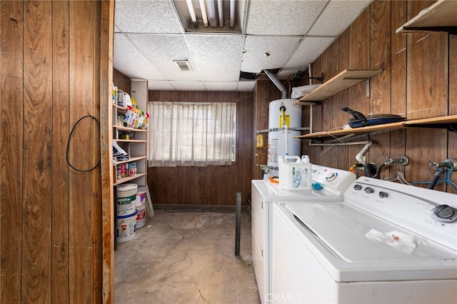 clothes washing area with wooden walls, laundry area, visible vents, washer and dryer, and water heater