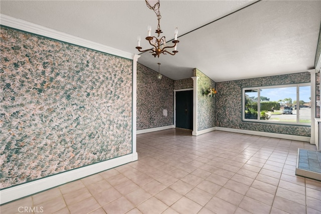 spare room with a chandelier, a textured ceiling, baseboards, and wallpapered walls