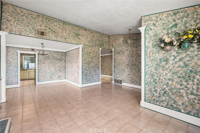 unfurnished room with wallpapered walls, baseboards, and visible vents