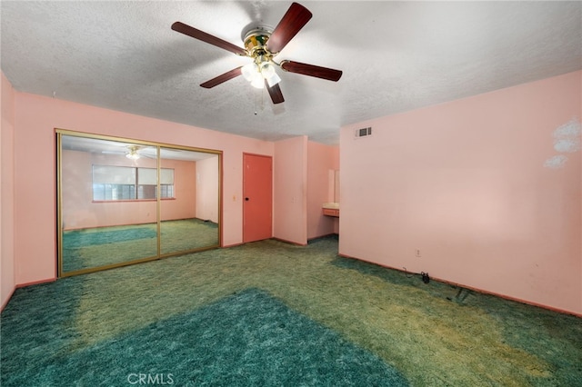 carpeted empty room with a ceiling fan, visible vents, and a textured ceiling