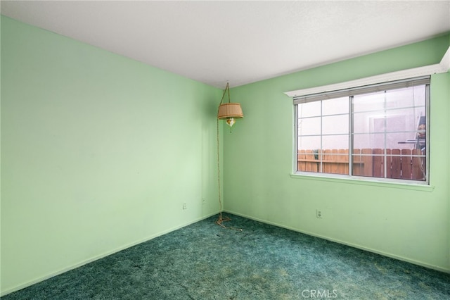 unfurnished room featuring baseboards and dark carpet