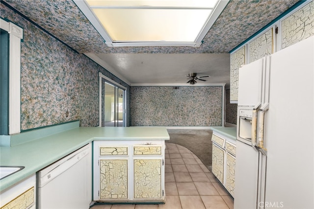 kitchen with light countertops, white appliances, a peninsula, and wallpapered walls