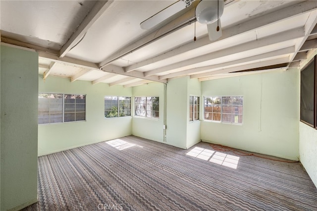 empty room with carpet, a ceiling fan, and beamed ceiling