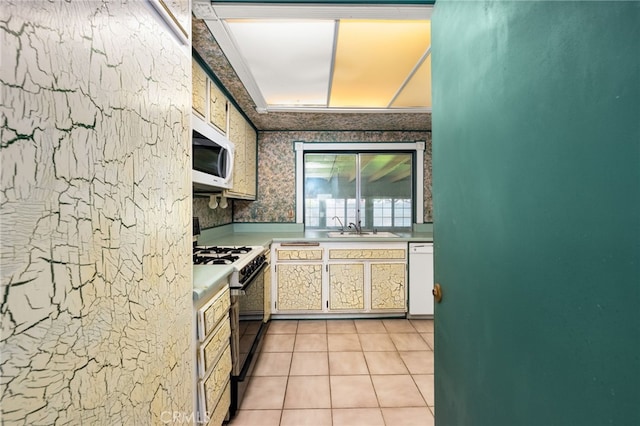 kitchen with white appliances, white cabinets, light countertops, a sink, and light tile patterned flooring