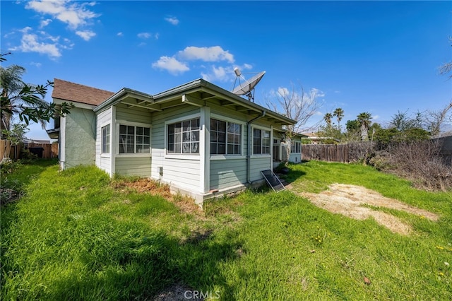 back of house featuring a lawn and fence