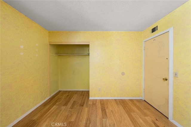 unfurnished bedroom featuring baseboards, light wood-style flooring, visible vents, and a closet