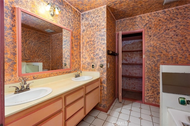 bathroom with double vanity, wallpapered walls, and a sink