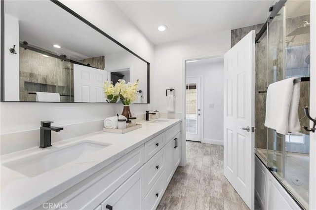 bathroom featuring enclosed tub / shower combo, vanity, and hardwood / wood-style floors