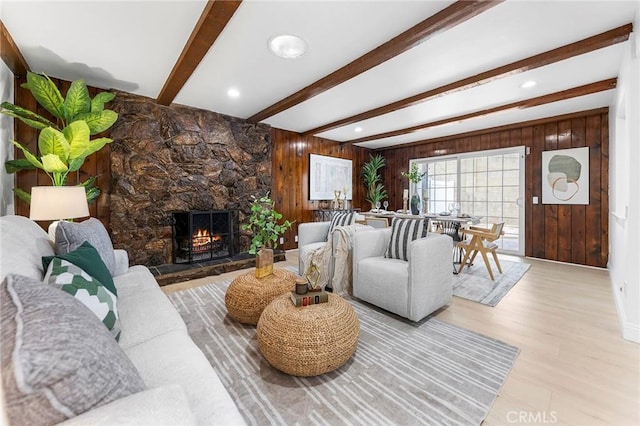 living room featuring a fireplace, light hardwood / wood-style floors, wooden walls, and beamed ceiling