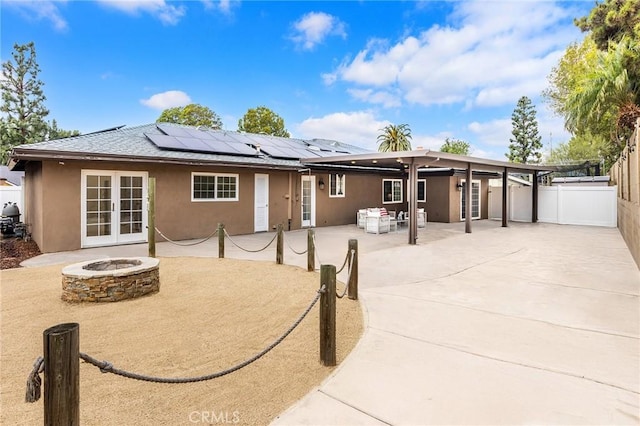 back of house with solar panels, a patio area, french doors, and an outdoor fire pit