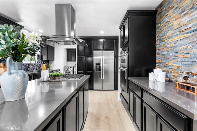 kitchen featuring island range hood, tasteful backsplash, sink, stainless steel appliances, and light wood-type flooring