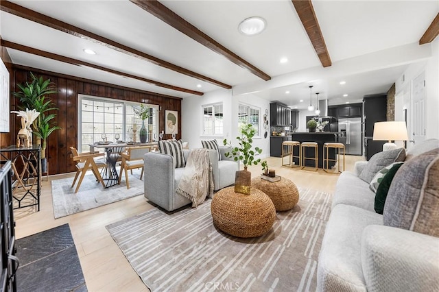 living room featuring wooden walls, beam ceiling, and light wood-type flooring