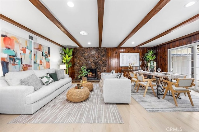 living room featuring beam ceiling, wooden walls, and light hardwood / wood-style floors