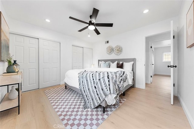 bedroom featuring ceiling fan, two closets, and light hardwood / wood-style floors