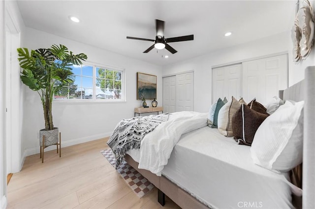 bedroom featuring multiple closets, ceiling fan, and light wood-type flooring