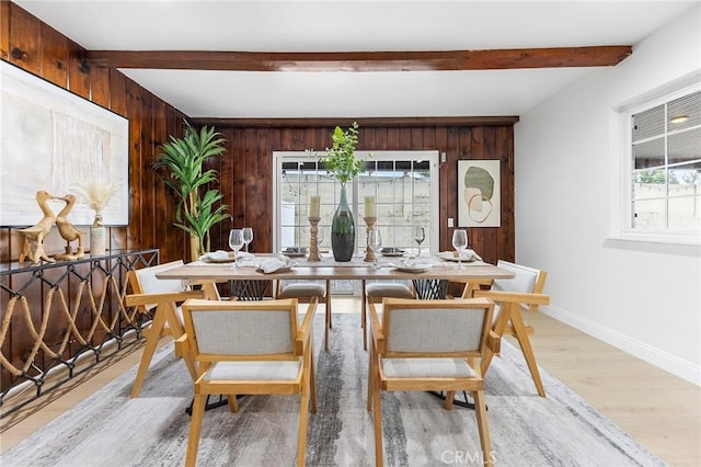 dining area with beamed ceiling, light wood-type flooring, and wood walls