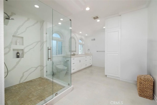 bathroom with a marble finish shower, recessed lighting, visible vents, toilet, and vanity