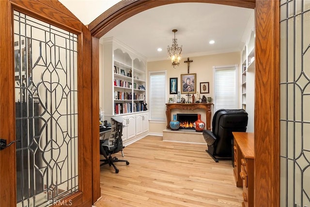 home office featuring built in shelves, crown molding, recessed lighting, light wood-type flooring, and a lit fireplace