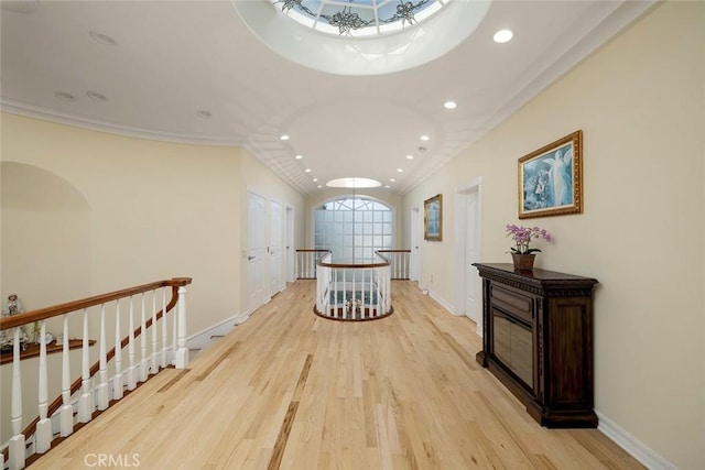 corridor with baseboards, ornamental molding, an upstairs landing, light wood-style floors, and recessed lighting