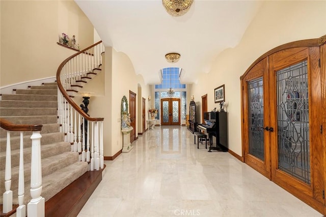 foyer entrance with baseboards, arched walkways, and french doors