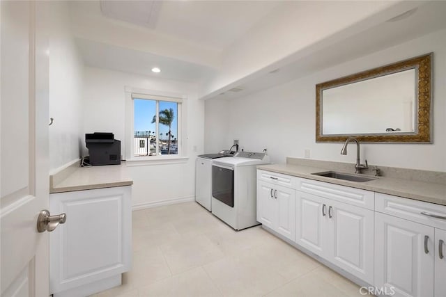 laundry area with washing machine and clothes dryer, recessed lighting, cabinet space, a sink, and baseboards