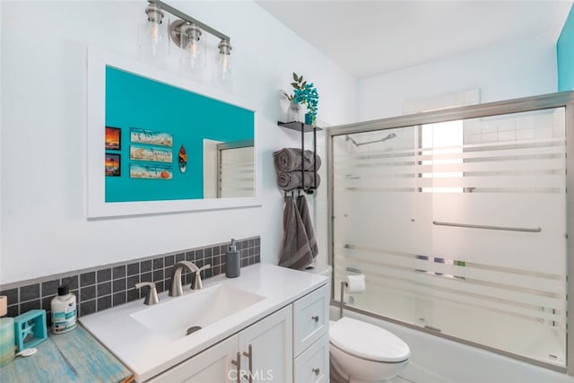 full bathroom featuring toilet, vanity, bath / shower combo with glass door, and decorative backsplash