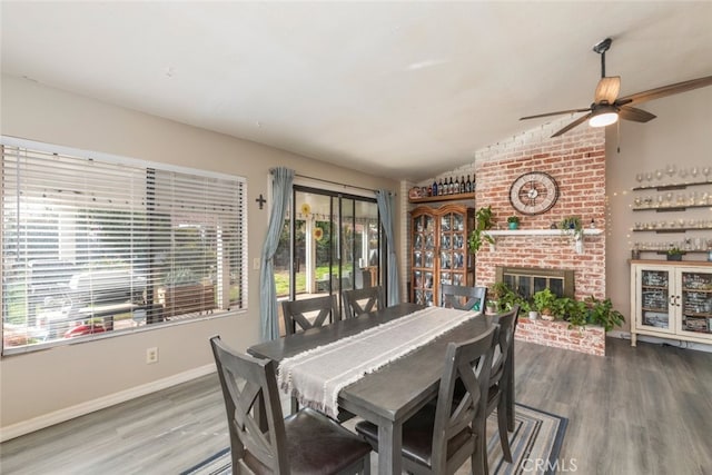 dining space with lofted ceiling, hardwood / wood-style floors, and a brick fireplace